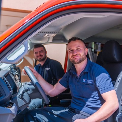 Im Feuerwehrfahrzeug – Zwei Feuerwehrmänner im Führerhaus