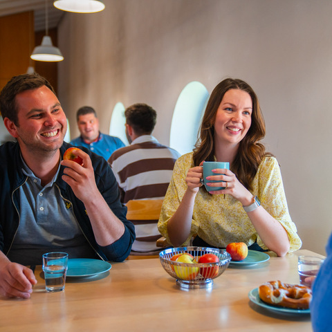 Pause im Aufenthaltsraum – Mitarbeitende unterhalten sich bei Kaffee, Obst und Gebäck