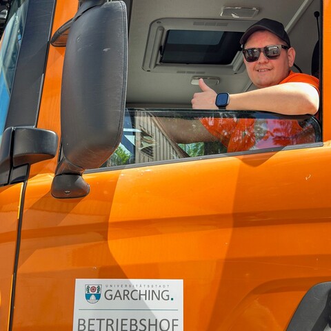 Mitarbeiter in Fahrerkabine eines städtischen Fahrzeugs zeigt Daumen hoch und lächelt