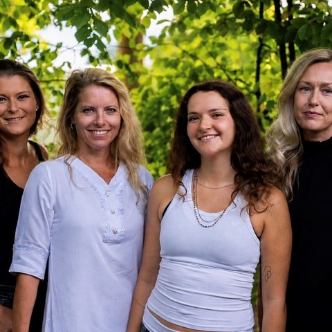 Zwei Frauen am Eingang eines Gebäudes lächeln in die Kamera, im Hintergrund bunte Dekoration