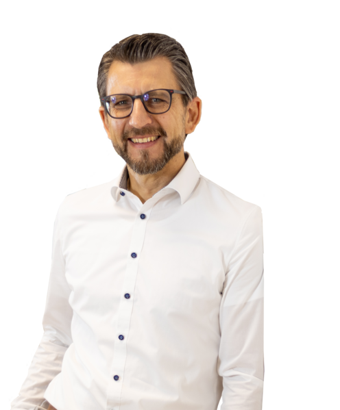 Dirk Kastner stehend im weißem Hemd mit dunklen Knöpfen, blauer Hose, braunem Gürtel und Armbanduhr.