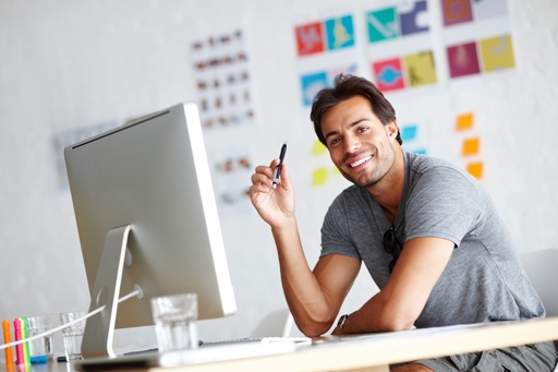 Happy man smiling while sitting at desk with computer