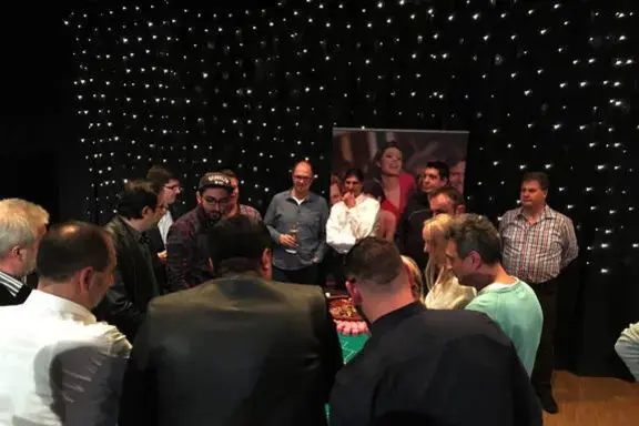 Große Gruppe von Gästen verfolgt gespannt das Spielgeschehen am Casino-Tisch bei einem Event von Rent-A-Casino