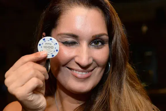 Lächelnde Frau hält einen Casino-Chip bei einem mobilen Casino-Event von Rent-A-Casino