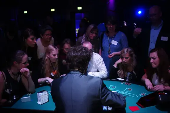 Junge Gäste verfolgen gespannt das Spiel am Black-Jack-Tisch bei einem Casino-Event