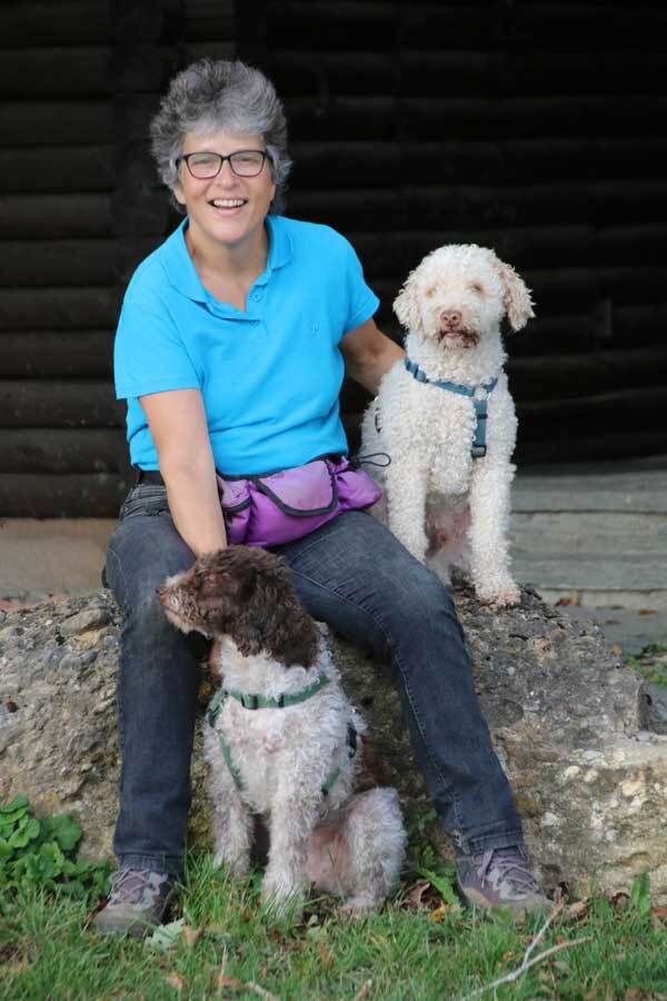 Claudia Greder sitzt auf einem Stein, neben sich ihre beiden Lagotto