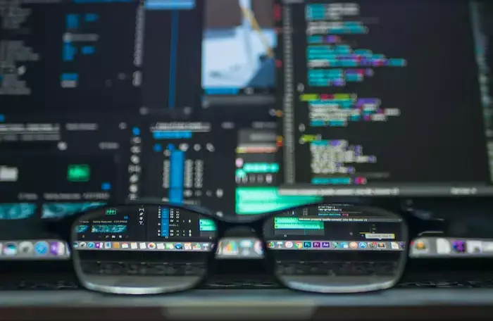 A pair of glasses set on a laptop with the laptop's screen in the background.