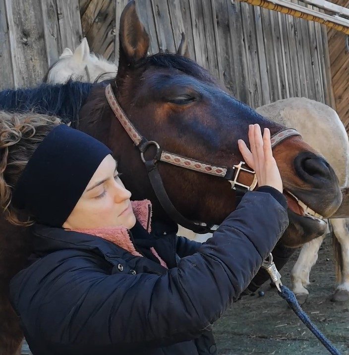 Isabelle berührt sanft ein Pferd