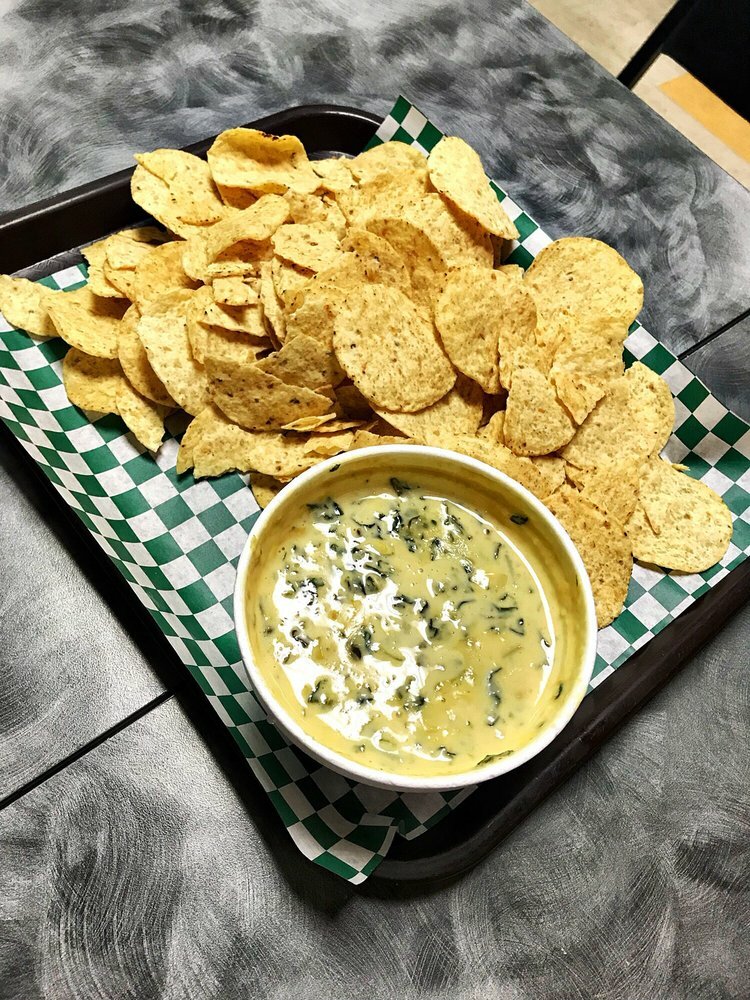 An order of spinach artichoke dip served with chips.