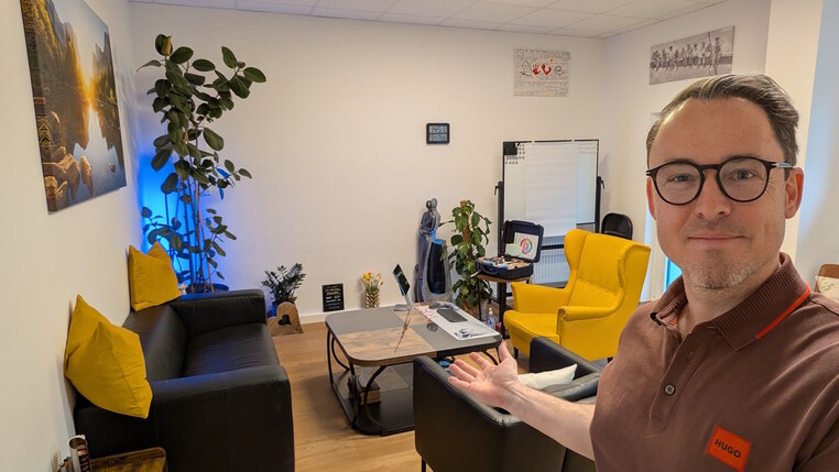 Mag. Streitberger sitzt auf einem auffälligen Ohrenstuhl. Er hält einen Stift und Moderationskarten in den Händen. Seine Körperhaltung ist aufrecht und aufmerksam. Er blickt in die Richtung der nicht sichtbaren Klient:innen und hört ihnen gespannt zu.