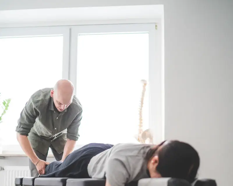 Chiropraktiker Andrew Klinkert behandelt den Rücken eines Patienten auf der Behandlungsliege