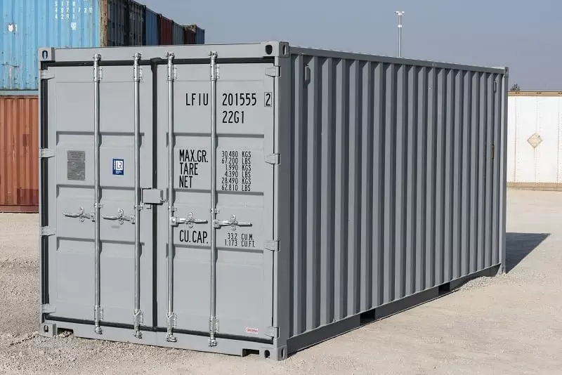A grey 20 DV shipping container sitting in a parking lot.