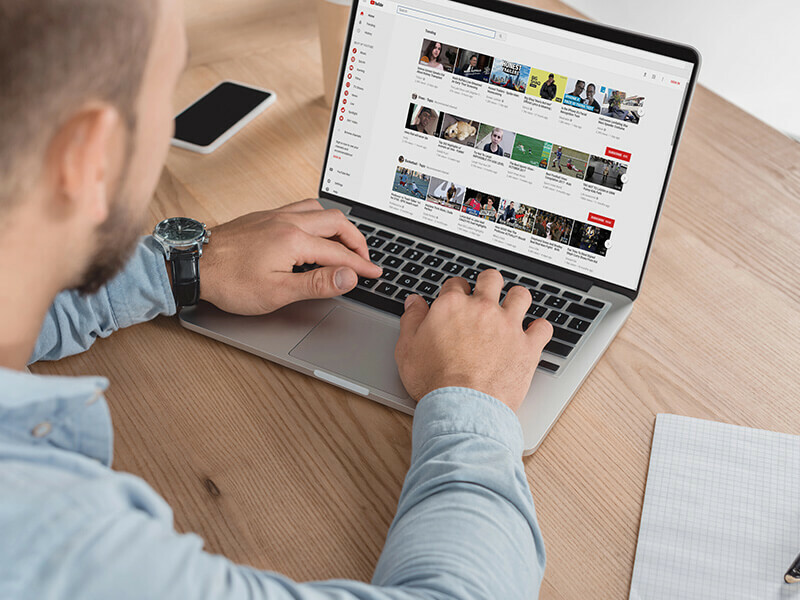 en mann sitter med en pc ved et skrivebord i tre med youtube på skjermen