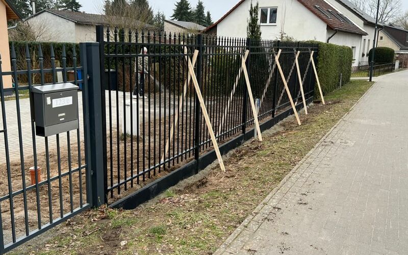 Metallzaun mit senkrechten Stäben in Anthrazit, inklusive Tor mit Briefkasten, neu installiert vor einem Haus.