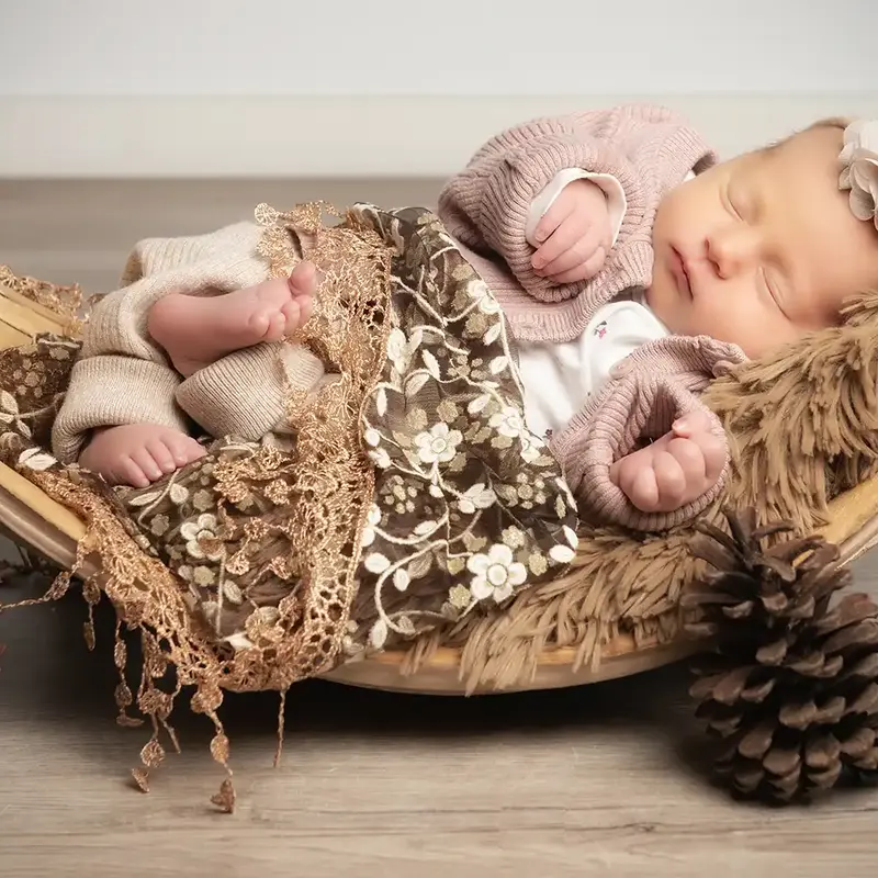 Schlafendes Baby in Halbschale mit Zapfen
