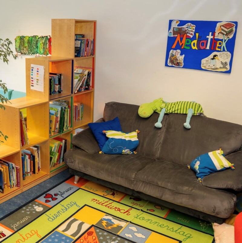 Gemütige Leseecke mit Sofa, Bücherregal und Teppich mit Wochentagen