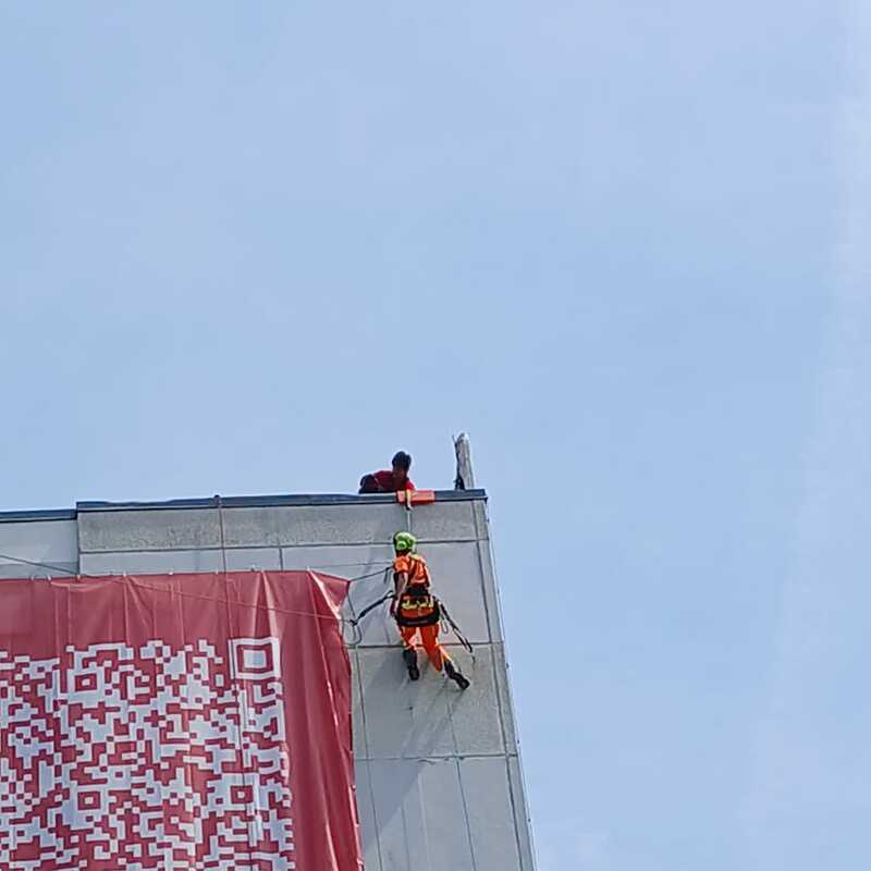 Kletterer befestigt sich an Hochhausfassade