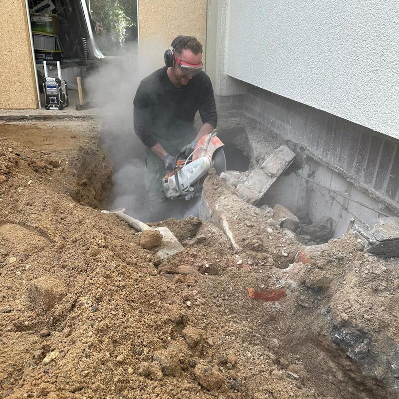 Staubige Trennarbeiten an Hauswand im Erdreich