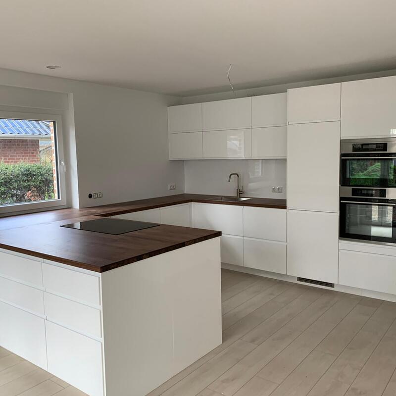 Küchenmontage Berlin – weiße Hochglanzküche mit Kücheninsel und dunkler Holzarbeitsplatte