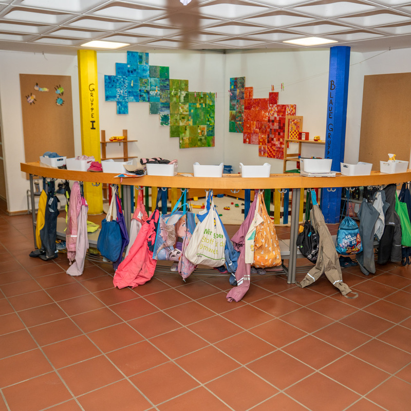 Garderobenbereich im Kindergarten mit bunten Taschen und Jacken