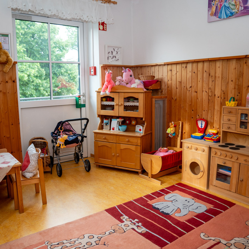 Spielbereich mit Holzküche, Tisch und Kuscheltieren