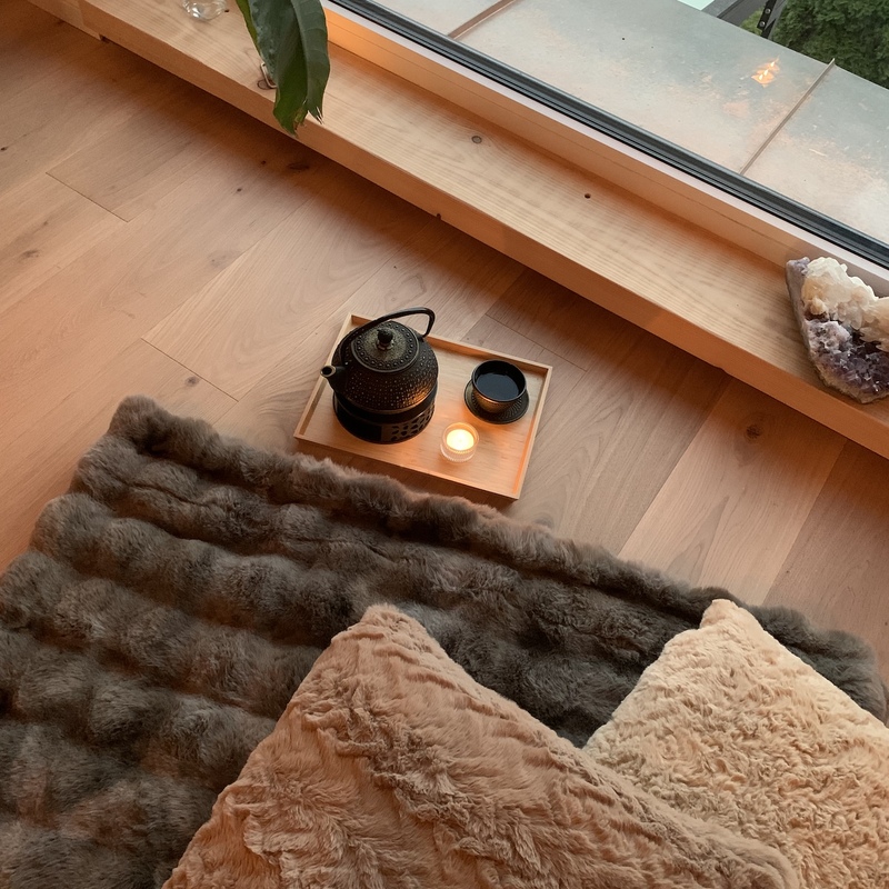 Nahaufnahme eines Fenstersims mit Kissen, Tee-Set und brennender Kerze