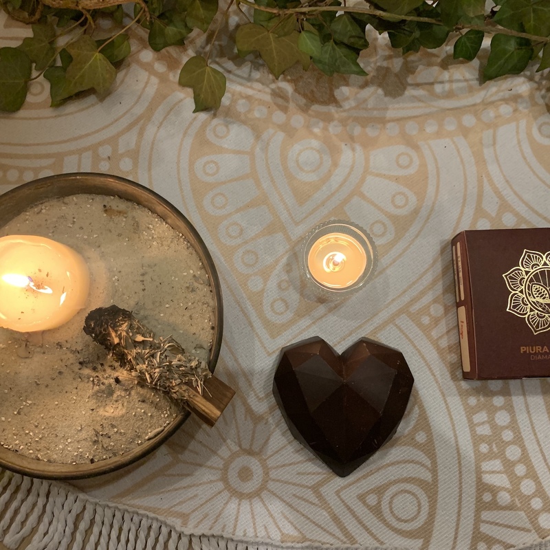 Detailaufnahme eines Altars mit Kerzen, Feder, Herzobjekt und Mandala-Tuch