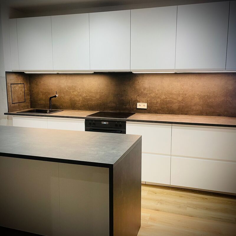 Küchenmontage Berlin – weiße Einbauküche mit dunkler Steinarbeitsplatte und integriertem Kochfeld