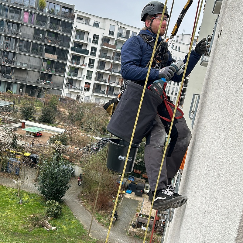 Kletterer bohrt an Hauswand