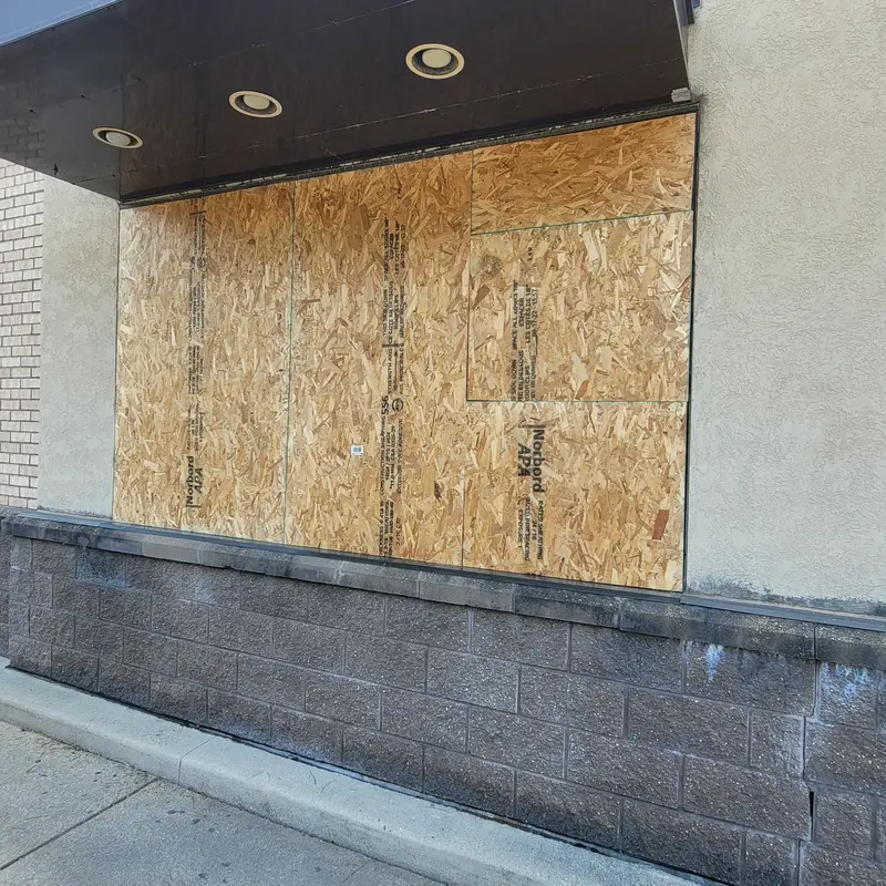 Boarded up and busted teller's window.