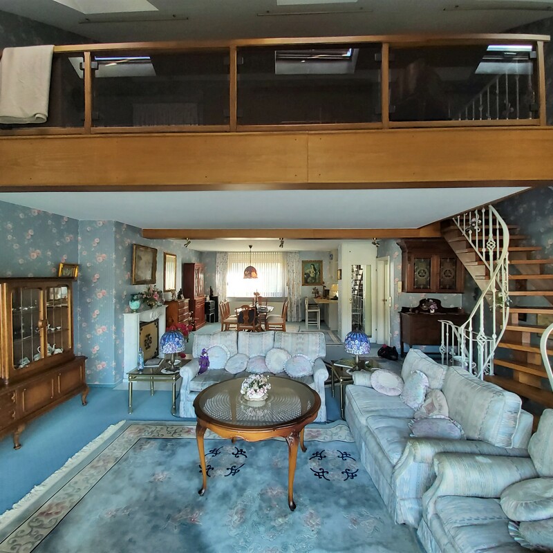 Großes Wohnzimmer mit Galerie, Wendeltreppe und antikem Mobiliar