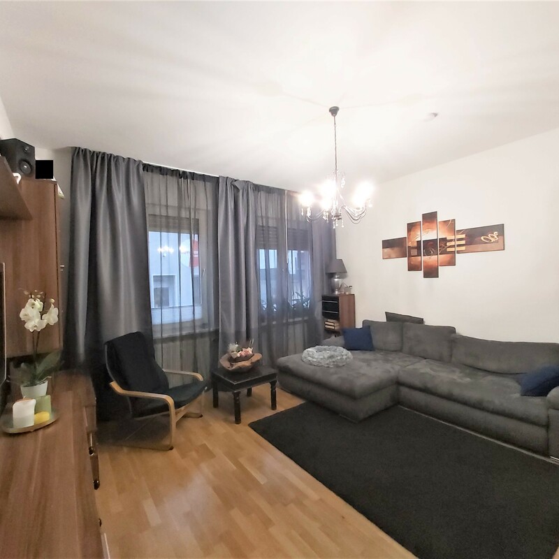 Wohnzimmer mit Ecksofa, Holzfußboden und dunklen Vorhängen