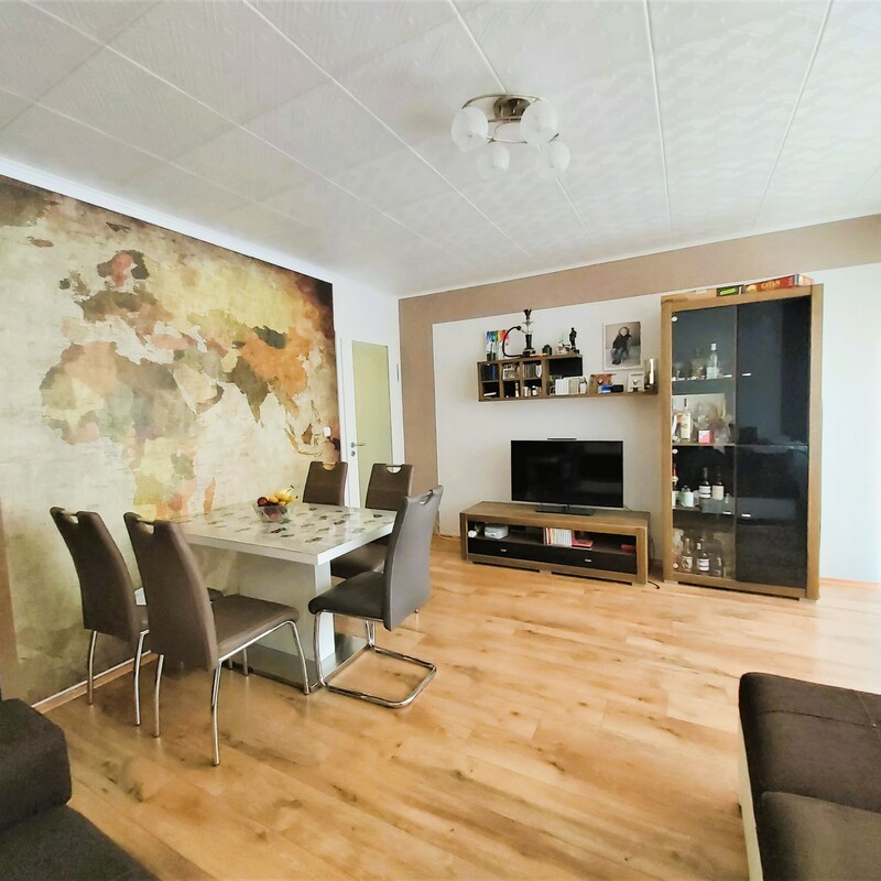 Modern eingerichtetes Wohnzimmer mit Esstisch, Fernseher und Weltkarten-Tapete