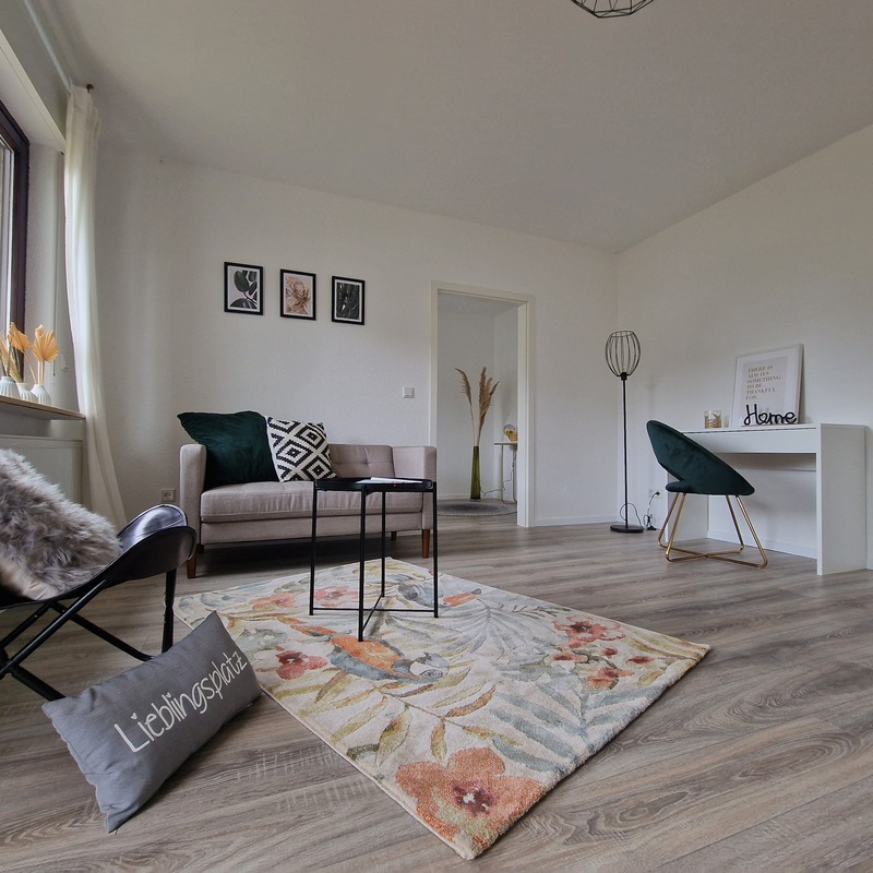 Modernes Wohnzimmer mit heller Einrichtung, Schreibtisch und gemütlicher Sitzecke