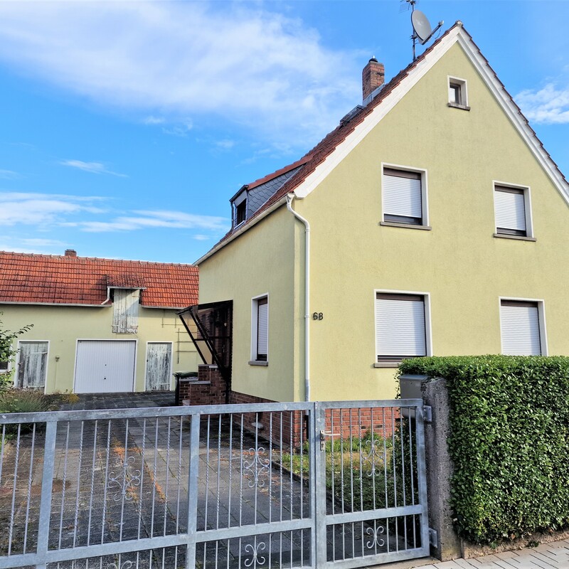 Einfamilienhaus mit gelber Fassade, Einfahrt und Vorgarten