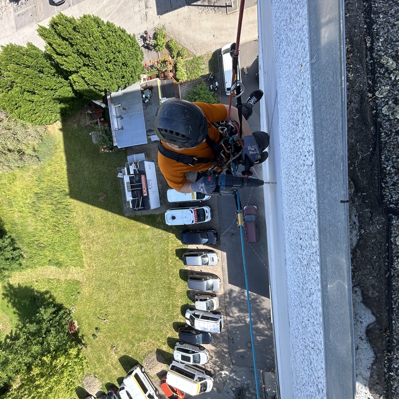 Kletterer arbeitet an Dachkante in großer Höhe