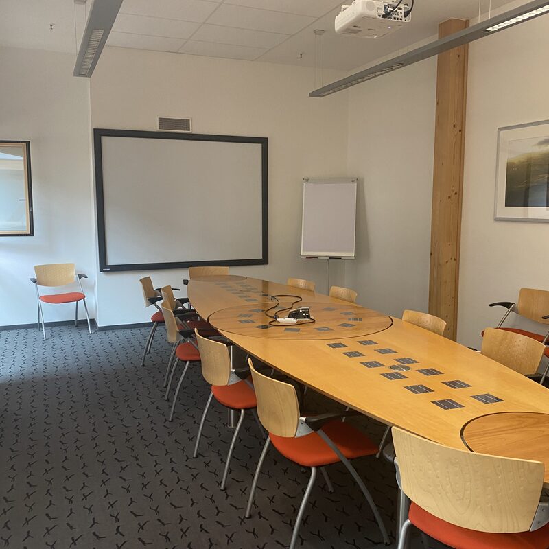 Besprechungsraum mit ovalem Tisch, Stühlen und Whiteboard