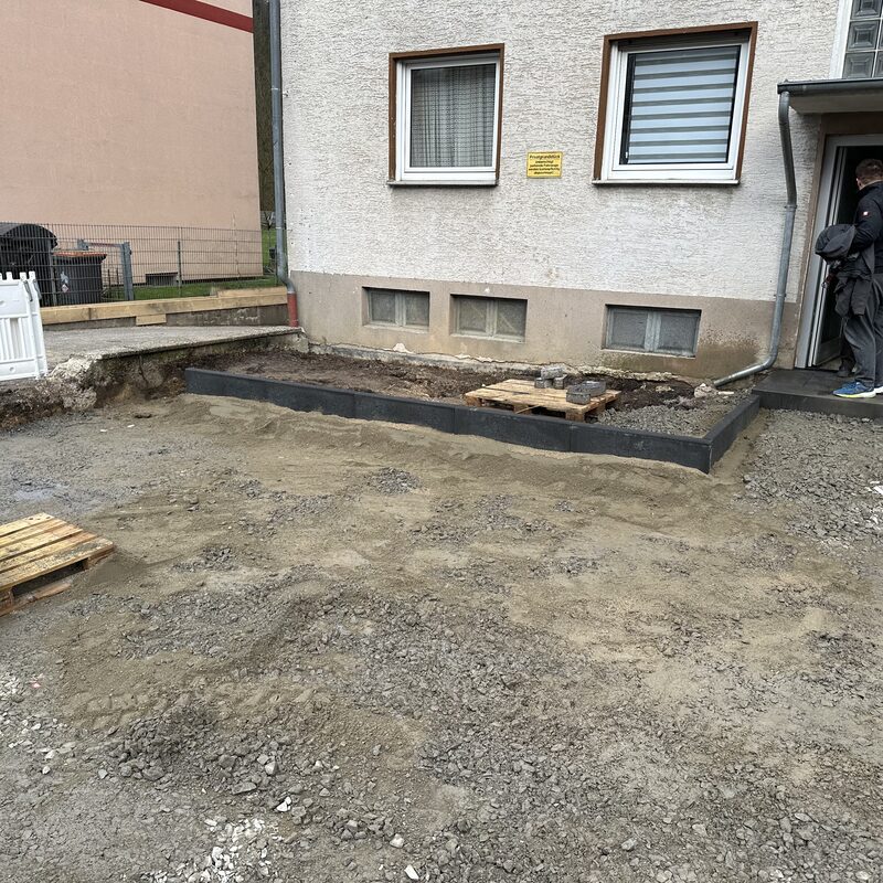 Aushubfläche an Gebäudewand mit Randsteinen

