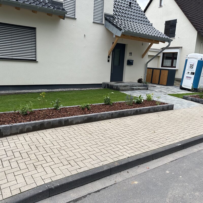 Eingangsbereich mit gepflasterter Einfahrt und Beeten