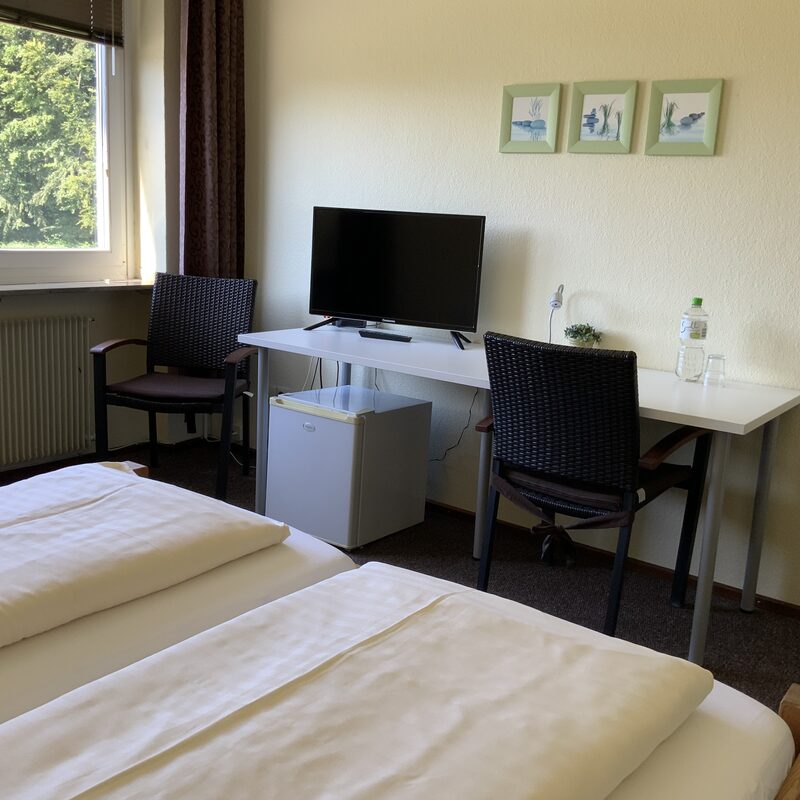 Zimmer mit Schreibtisch, TV und Kühlschrank