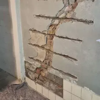 Nahaufnahme eines Spiralankers, der in eine Wand eingebracht wird, um bestehende Risse zu stabilisieren und Feuchtigkeit zu verhindern.