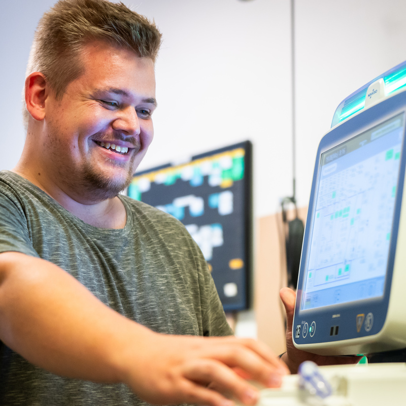 Mitarbeiter bedient lächelnd ein Dialysegerät