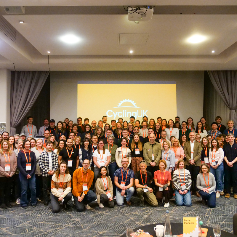 The whole of Cycling UK recently got together for our All-staff conference in Birmingham

(A photo of around 120 Cycling UK staff facing the camera, wearing orange Cycling UK lanyards. In the background there is a large presentation screen displaying the Cycling UK logo, which has a half cog above our name in white)