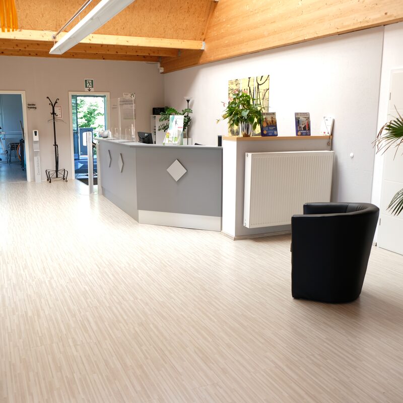 Moderner Empfangsbereich mit Tresen, Pflanzen und Sitzgelegenheit