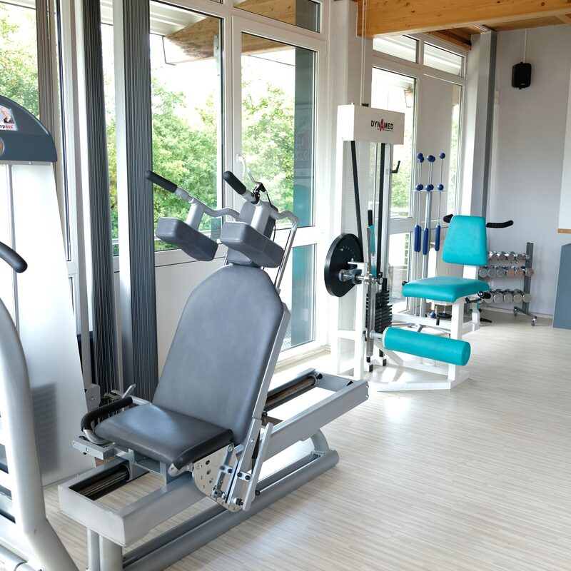 Heller Trainingsraum mit Kraftgeräten, Hanteln und Gymnastikbällen