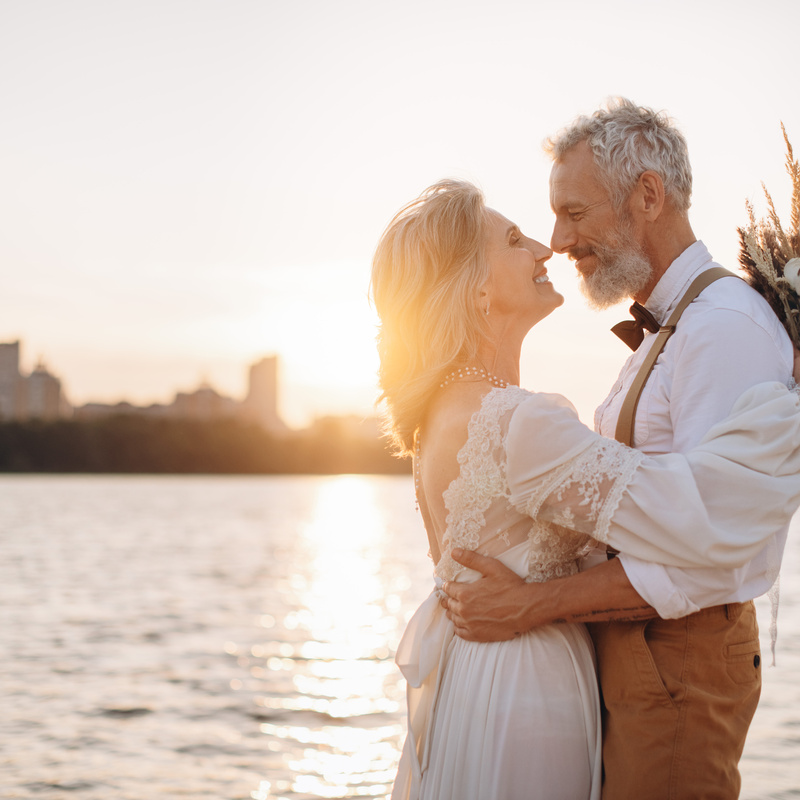 Älteres Brautpaar am Wasser bei Sonnenuntergang
