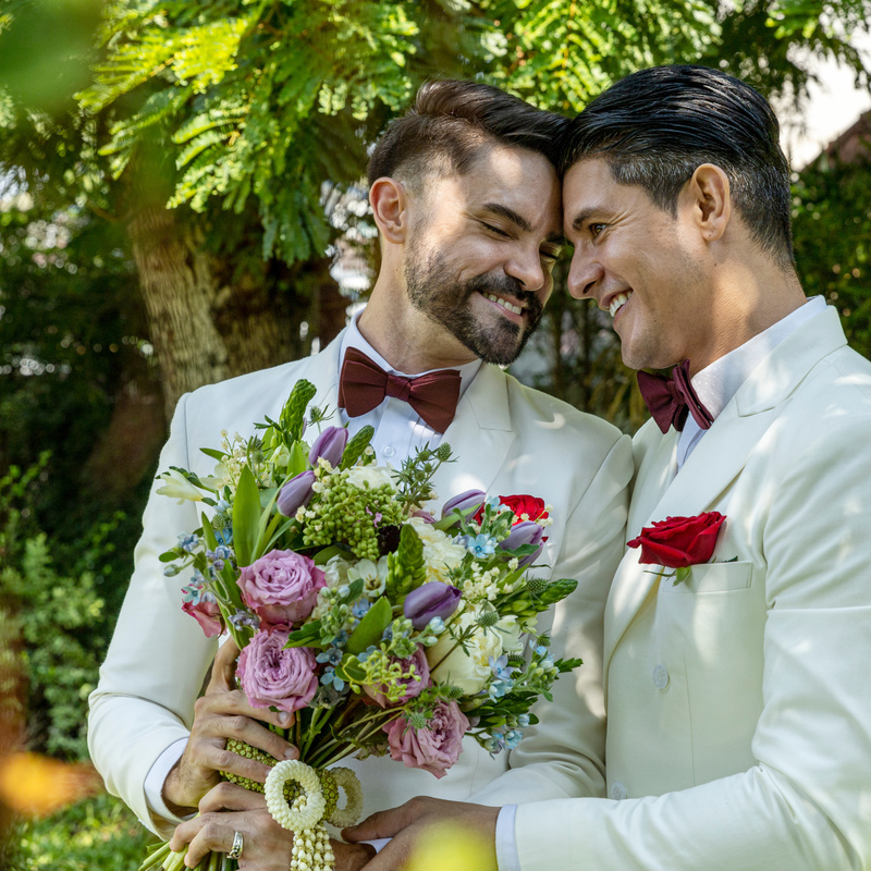 Zwei Bräutigame in Weiß mit Hochzeitsstrauß