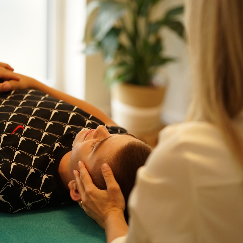 Junge liegt entspannt, Kopf wird gehalten