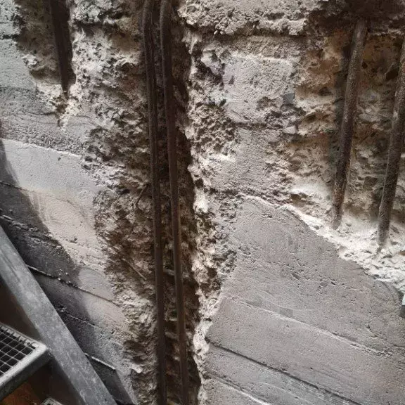 Deutlich sichtbare Schäden an einer Betonwand, bei denen die Armierungsträger freigelegt sind.