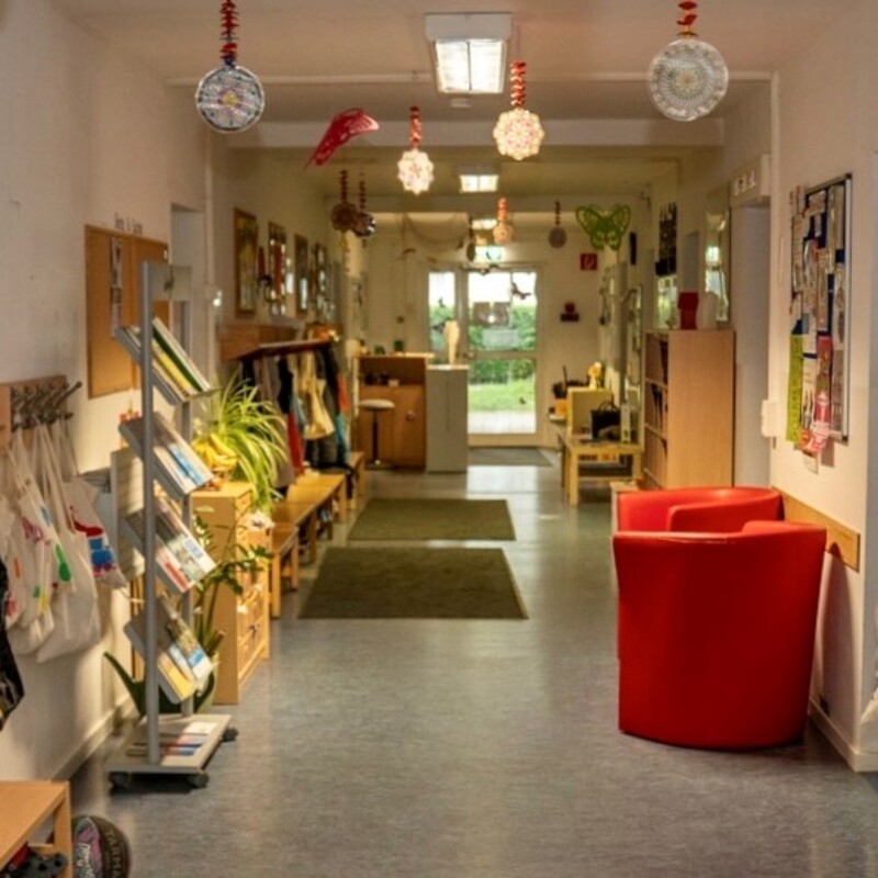 Heller Flur mit Garderobe, Sitzgelegenheiten und Kinderkunstwerken an den Wänden